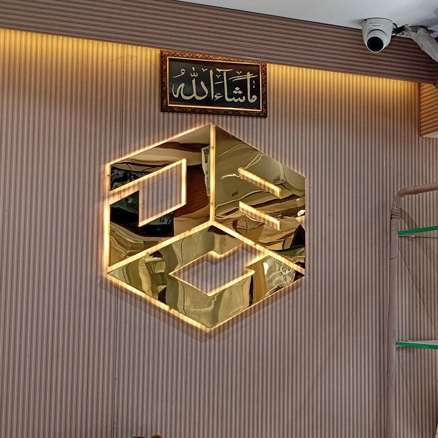 Corner of the boutique with the gold cube logo mounted on the wall above handbags