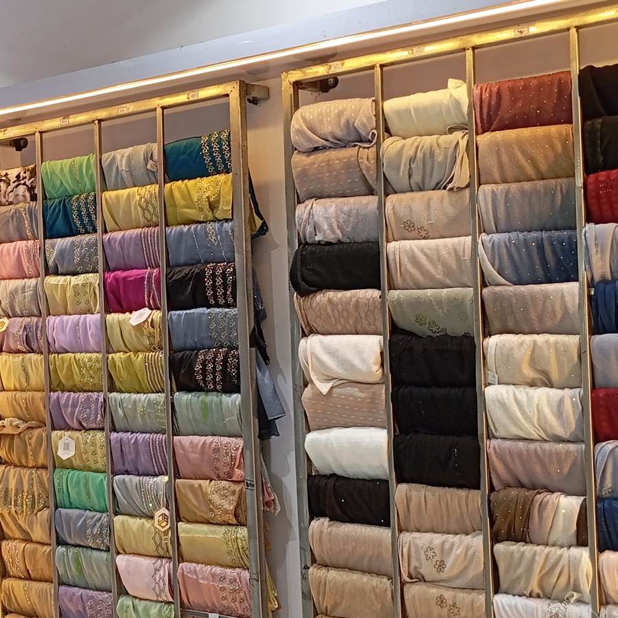 Trial room beside a wall of folded embellished fabrics