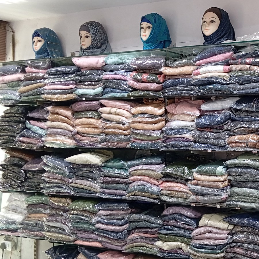 Hijab-draped mannequin heads above shelves of folded fabric